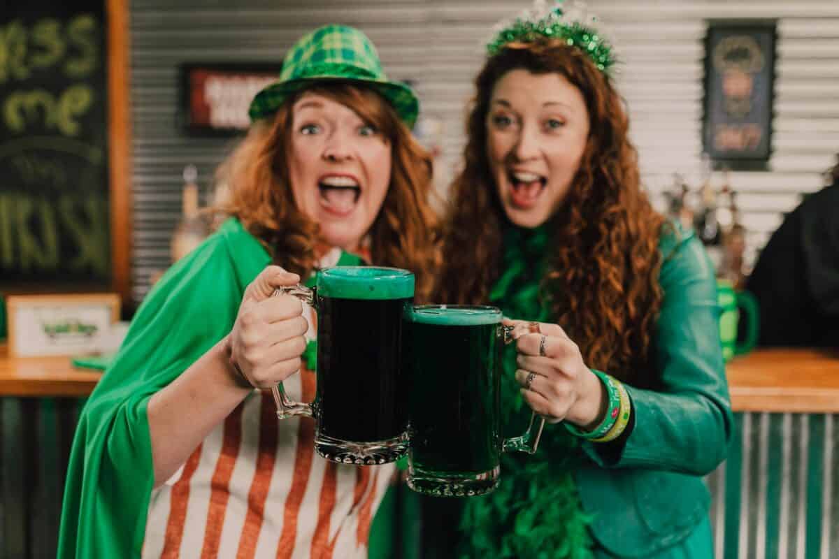 two women holding a green beers